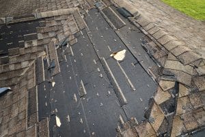 Damaged house roof with missing shingles after hurricane ian in florida. consequences of natural disaster