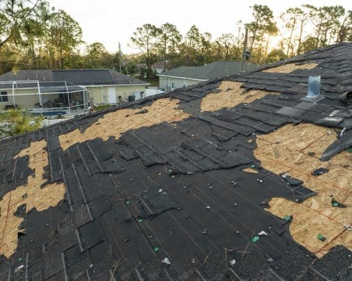 Ruined rooftop in need of repair. wind damaged house roof with missing asphalt shingles after hurricane ian in florida