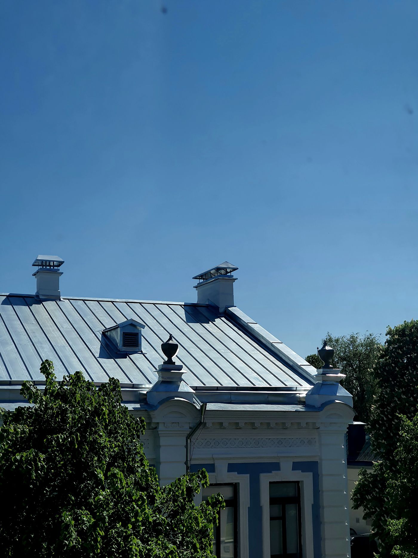 Blue-gray metal roof on a white house with a dormer