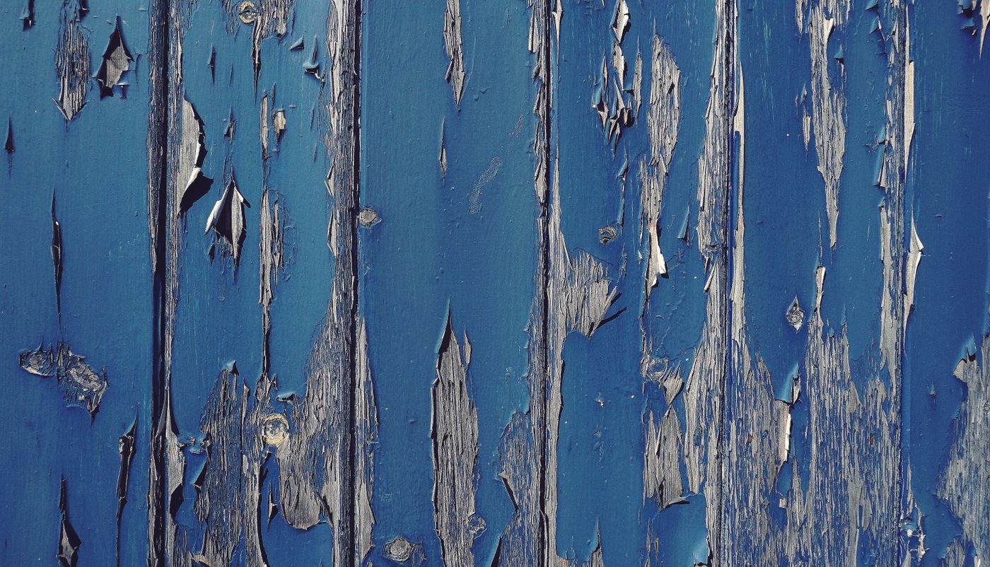 Blue paint peeling off weathered wood