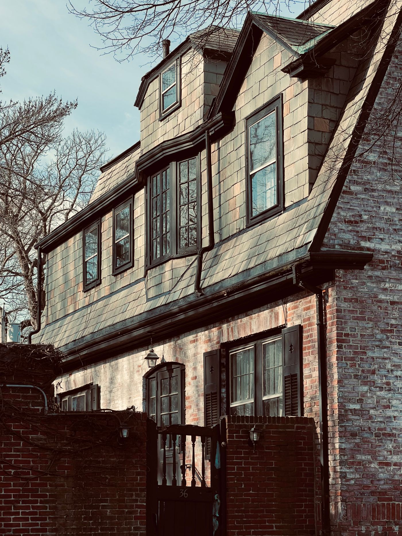 Brick house with a slate upper story and dormers