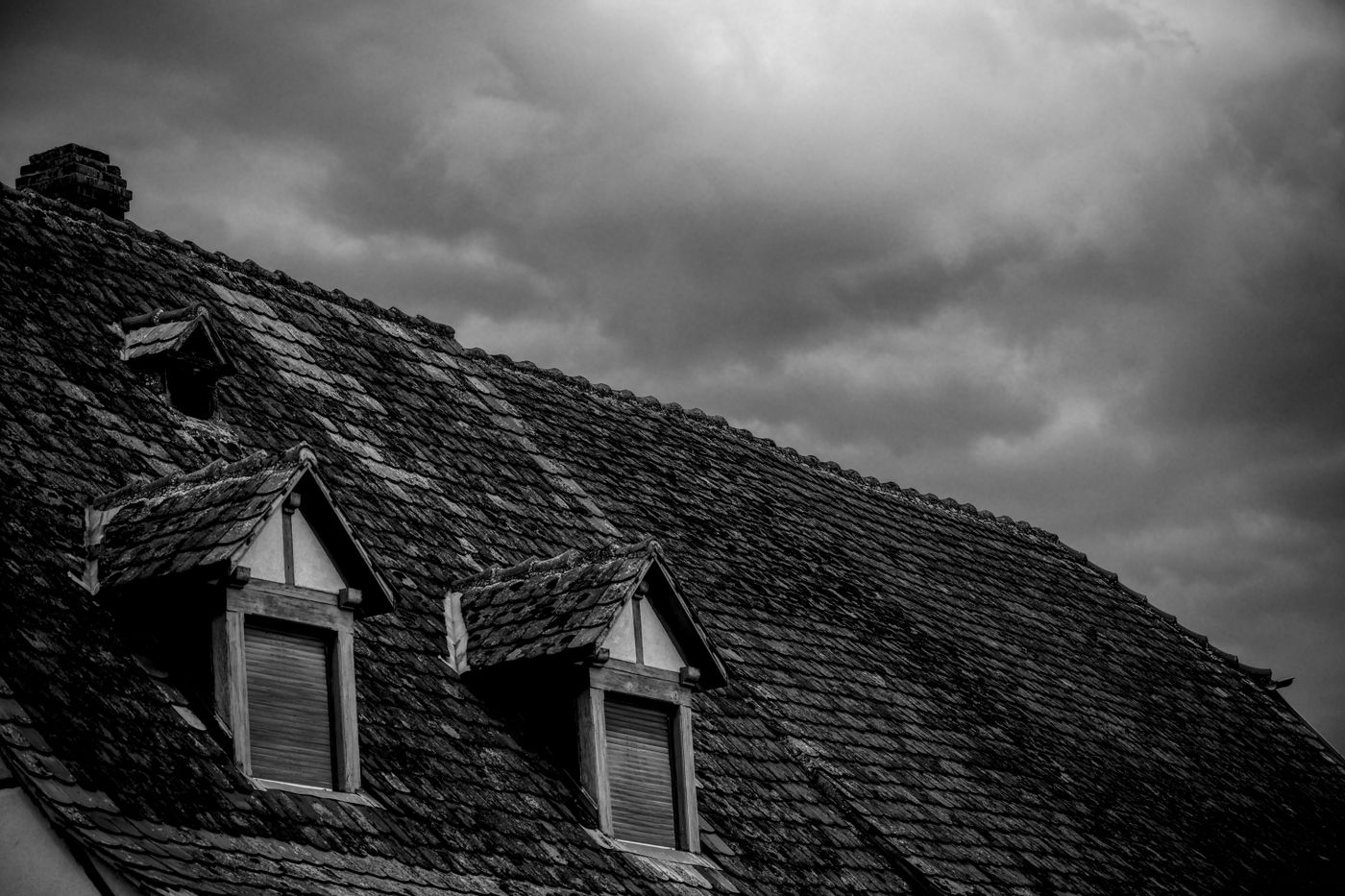 Dark roof with dormers under a stormy sky