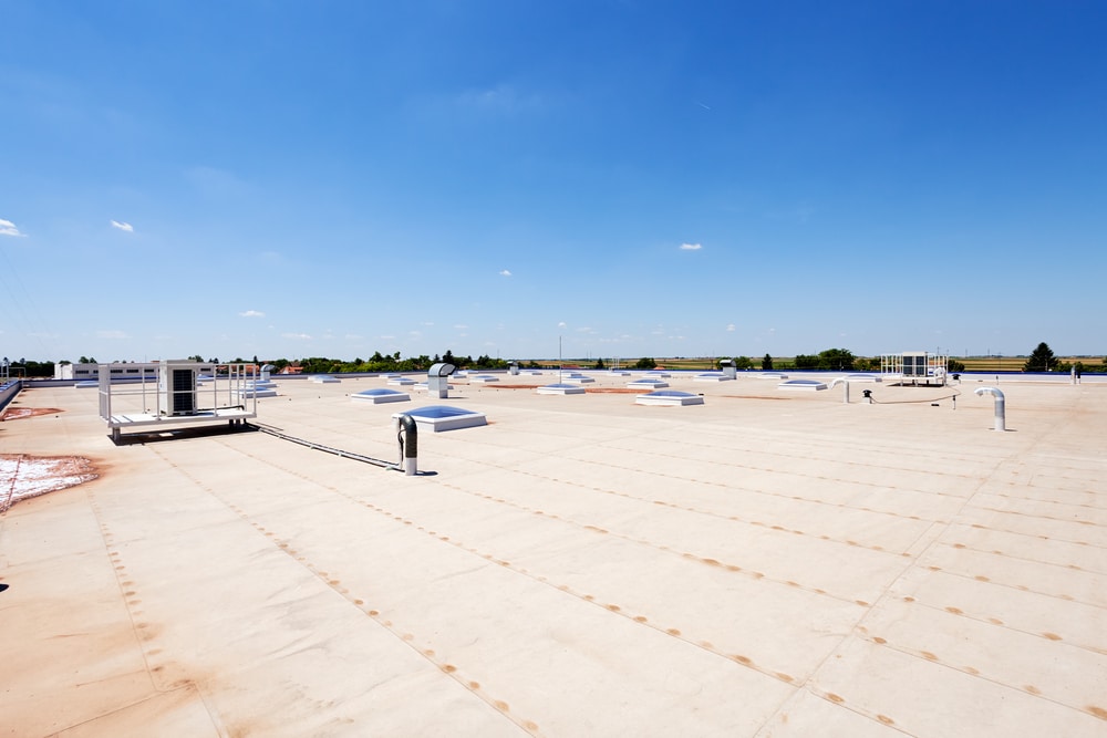 Wide flat commercial roof under a blue sky