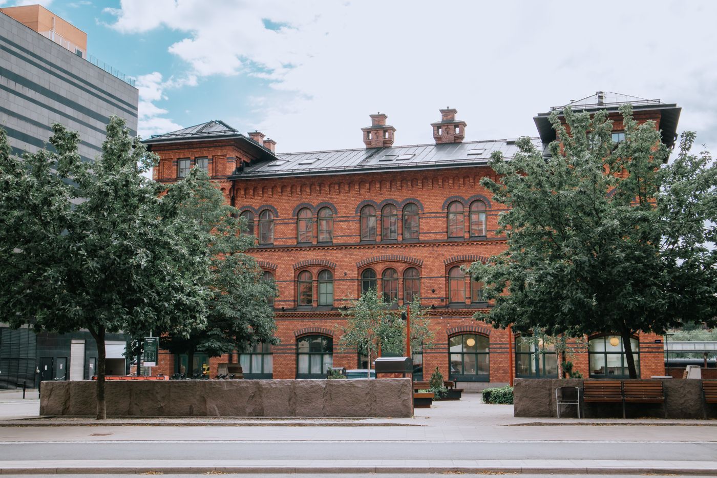Historic red brick building behind green trees