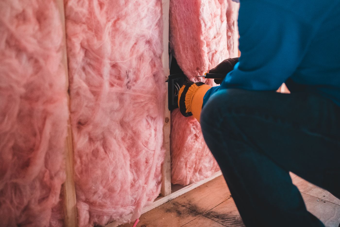 Installer fitting pink fiberglass insulation