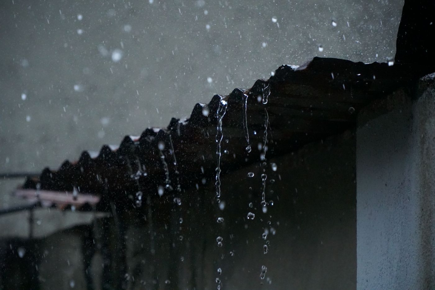 Rain dripping from a metal roof edge