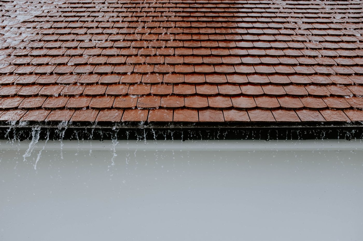 Rain running off a tile roof into the gutter