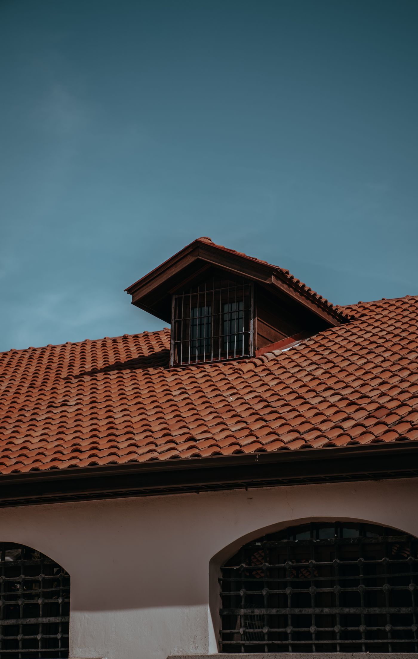 Red tile roof with a dormer above arched windows