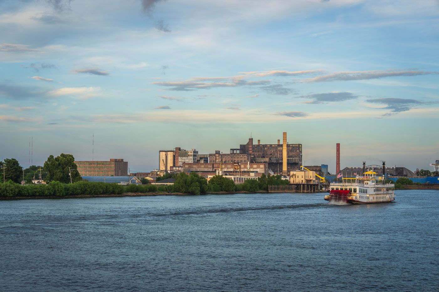 Riverboat on a wide river with buildings on the far bank