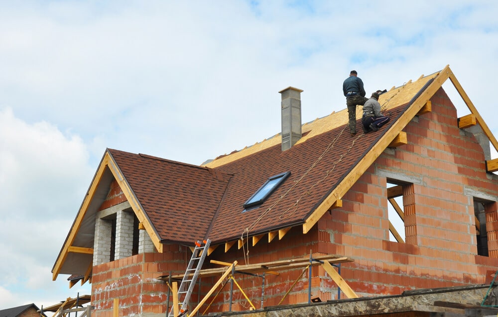 Roofers repairing a pitched shingle roof