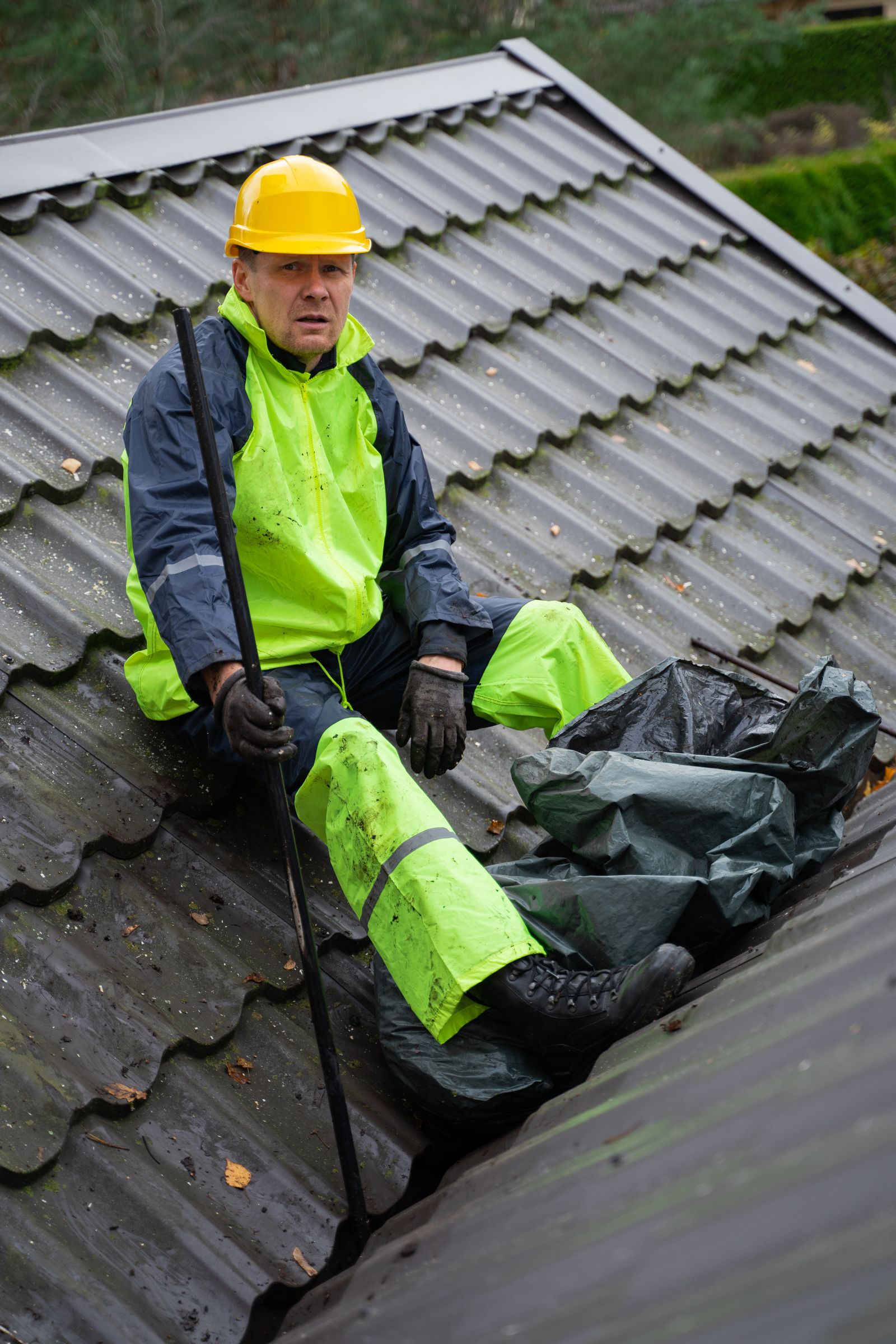 Roofer in high-visibility gear sitting on a metal roof