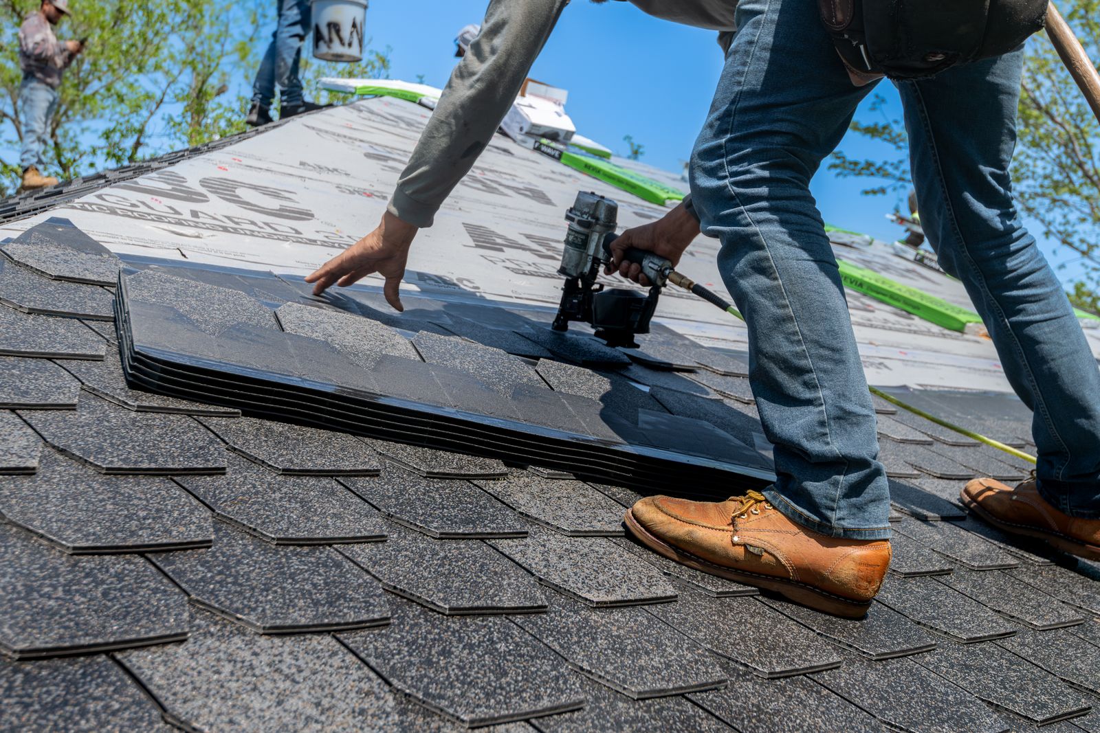 Roofer installing asphalt shingles during a roof replacement