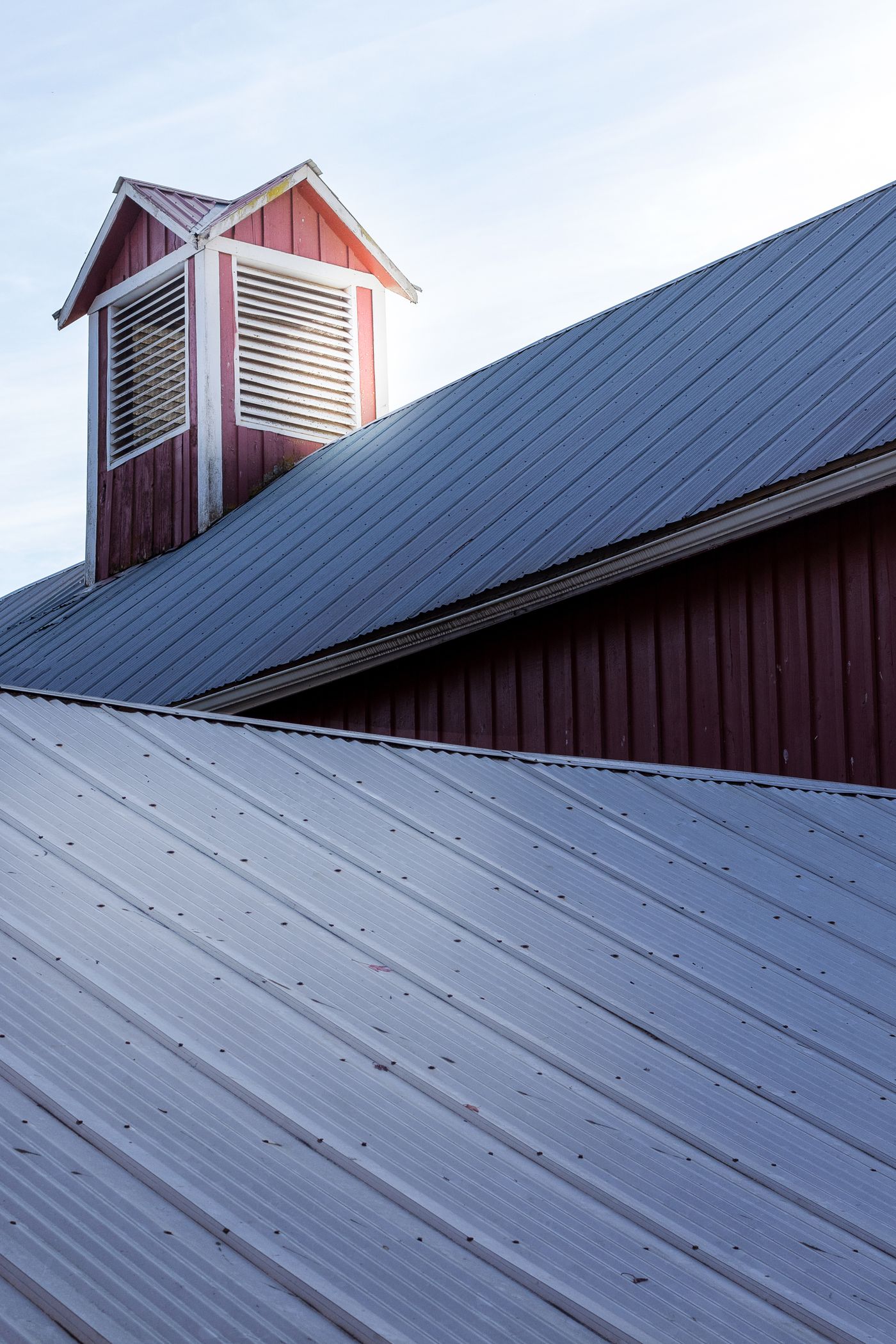 Standing seam metal roof below a red cupola vent