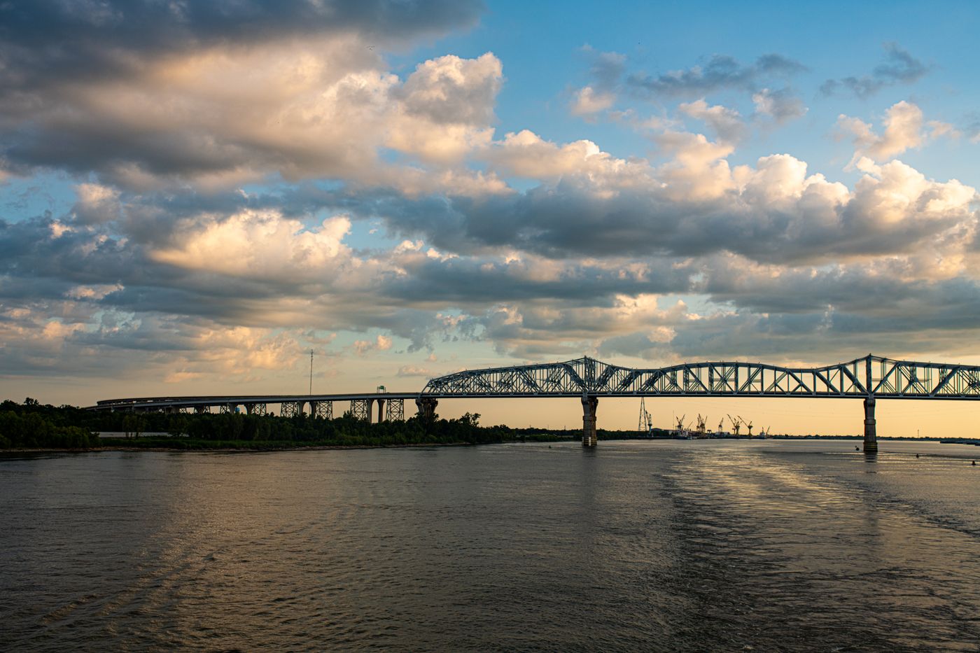 Steel bridge over a wide river at sunset