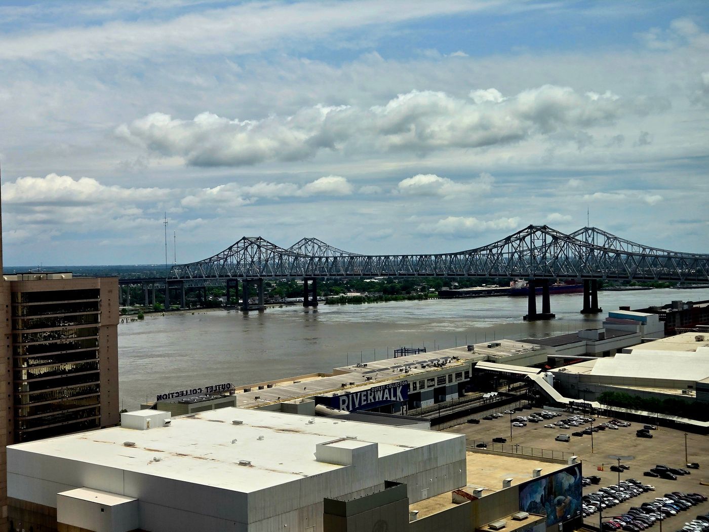 Steel truss bridge over a wide river beside downtown buildings