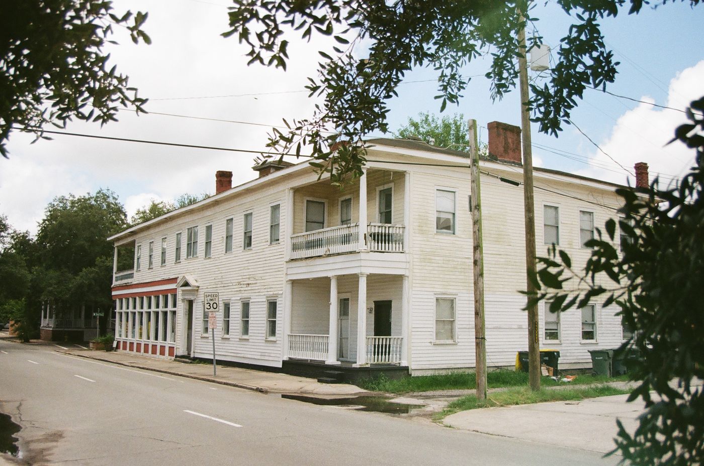 White two-story historic building on a tree-lined street