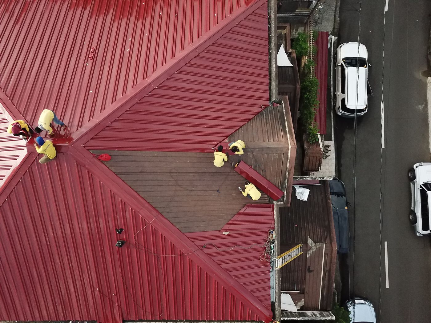 Workers on a red metal roof, seen from above