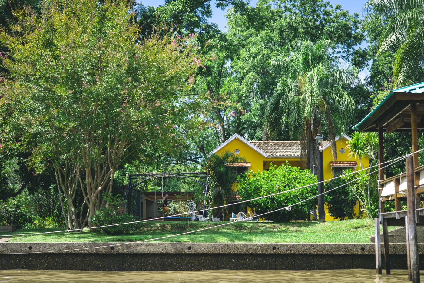 Yellow house among green trees beside the water
